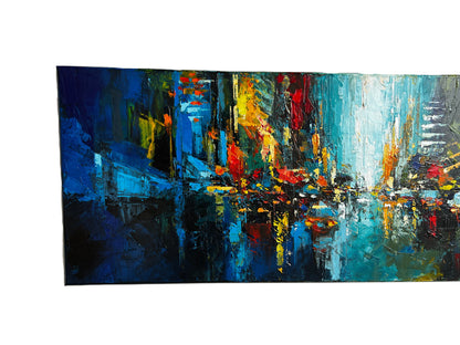 Abstract cityscape painting in a white frame on a wooden surface.