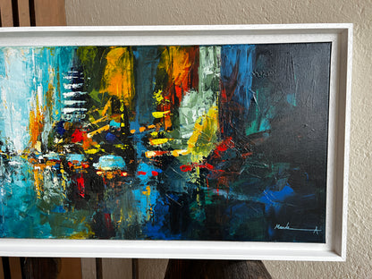 Abstract cityscape painting in a white frame on a wall.