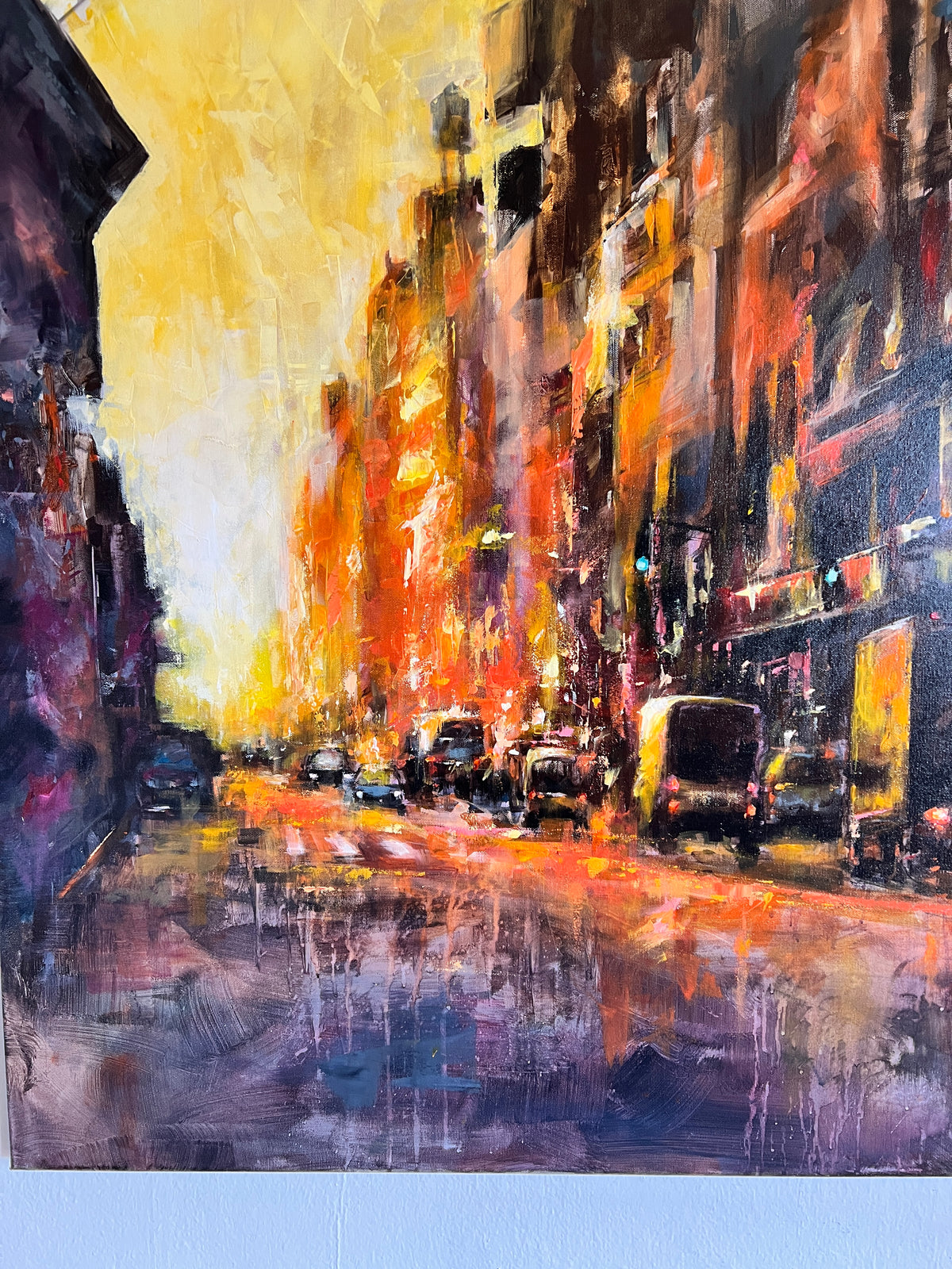 An impressionistic city street painting with tall buildings, glowing storefront lights, and vehicles, rendered in warm orange, yellow, red, and dark blue tones.