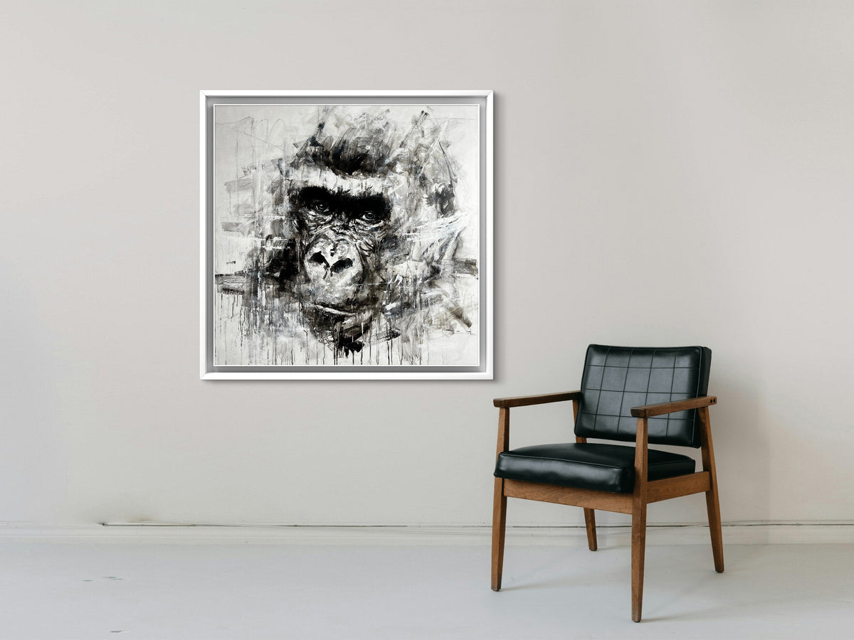 Framed abstract artwork of a gorilla's face on a wall above a chair.