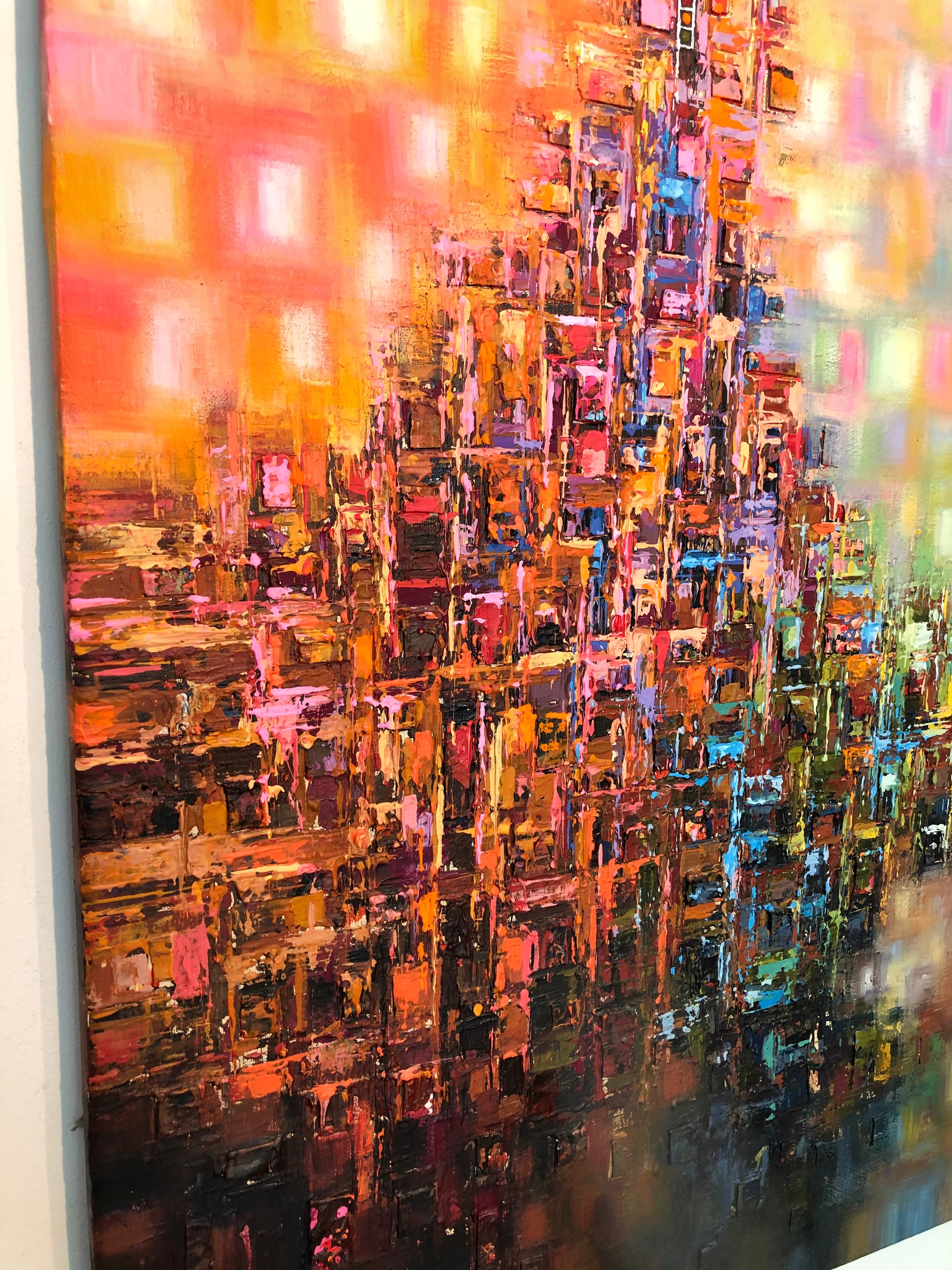 An abstract canvas painting featuring a textured, blocky cityscape or architectural composition in a rich palette of orange, red, pink, brown, black, and hints of blue and green.