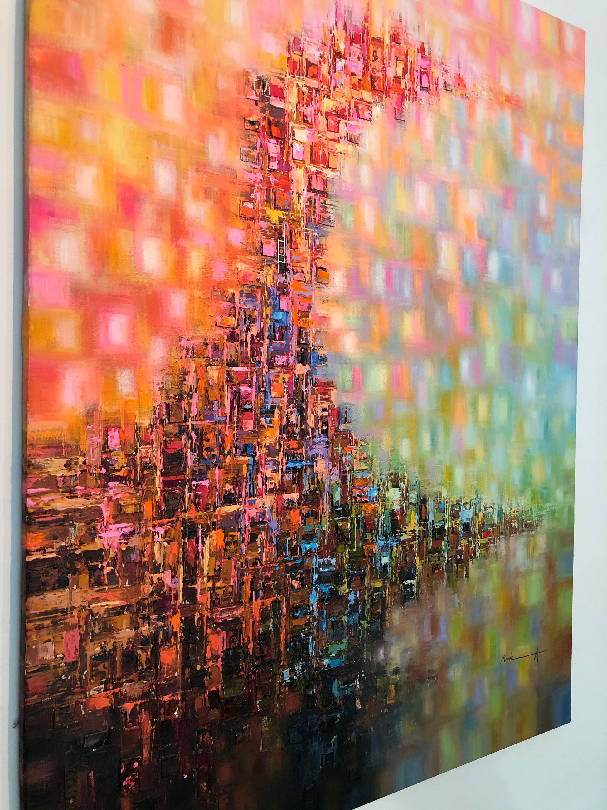 Abstract canvas wall art featuring a textured, blocky cityscape silhouette in warm orange, pink, and red tones blending into a green and blue gradient on the right, shown hanging on a white wall.